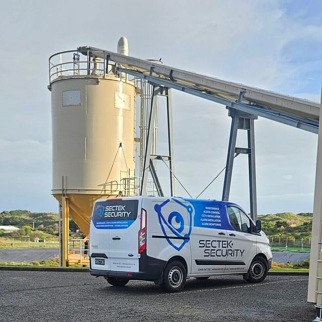 Sectek Security van parked at industrial site with yellow storage silo and conveyor belt system