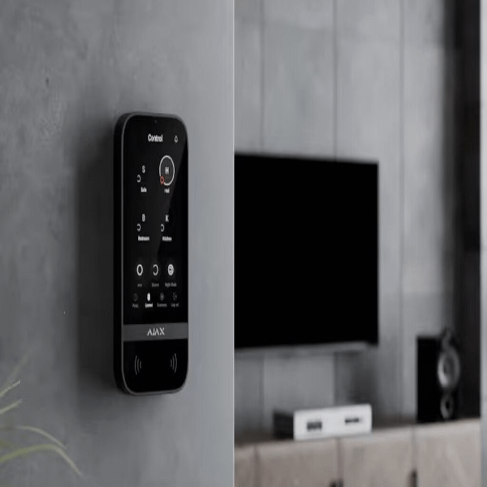 AJAX smart home security control panel mounted on wall next to TV in modern living room